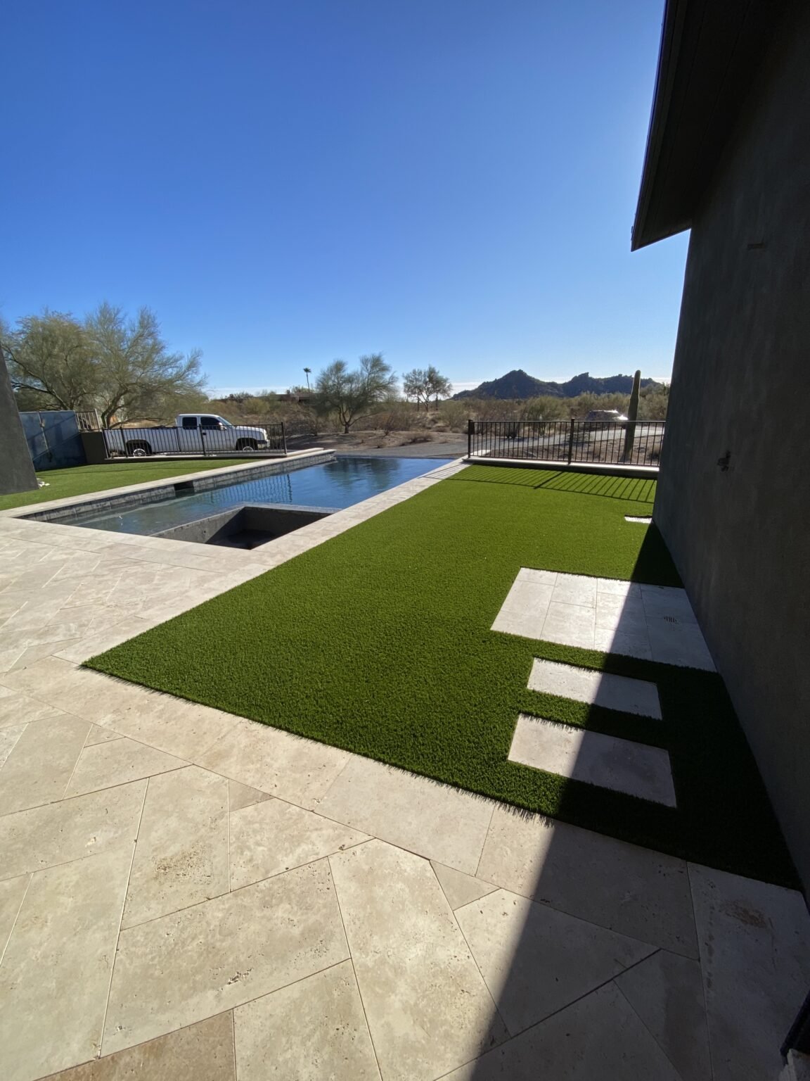 Scottsdale backyard with travertine pool deck and artificial turf installed by All Valley Turf, showcasing a luxurious low-maintenance design perfect for Arizona homes.